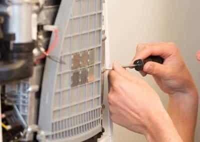 HVAC technician servicing an indoor air conditioning component during routine maintenance.